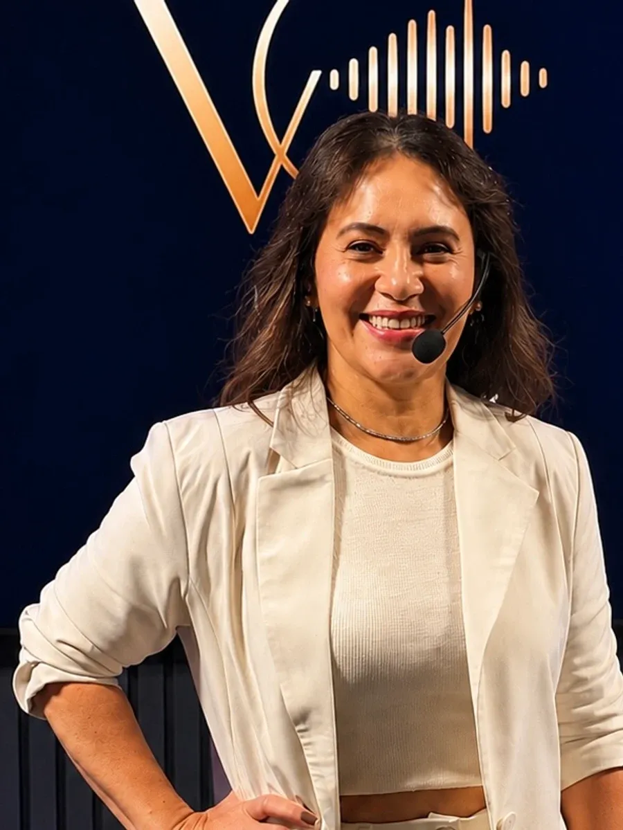 Simone Glaci, mentora do treinamento, no palco com microfone headset